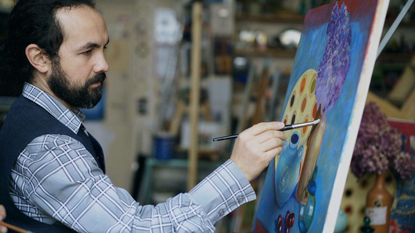 An artist working on a colourful painting in a studio
